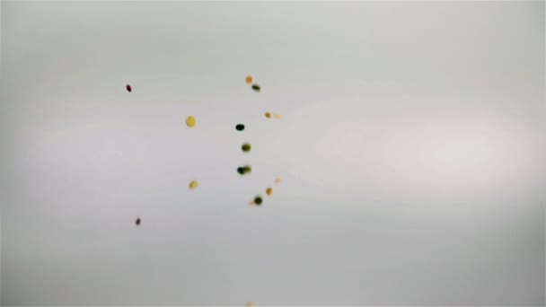 Diverses graines tombant sur le miroir en arrière-plan blanc au ralenti 