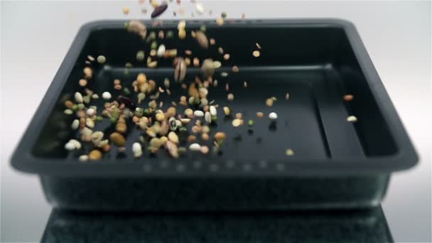 Varias semillas cayendo en placa en cámara lenta en fondo blanco — Vídeos de Stock