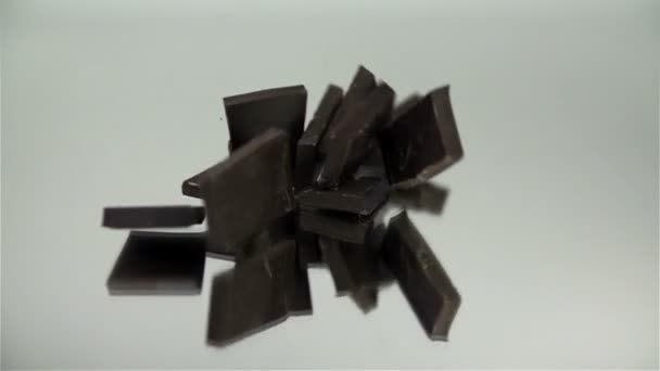 Stukken van chocolade vallen elk op een ander op spiegel — Stockvideo