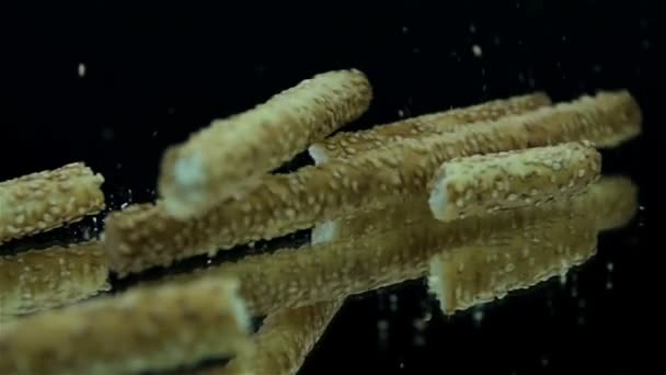 Salty sticks falling on black background in slow motion — Stock Video