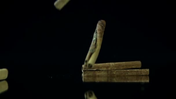 Kousky skořice, dopadající v pomalém pohybu na černé pozadí — Stock video