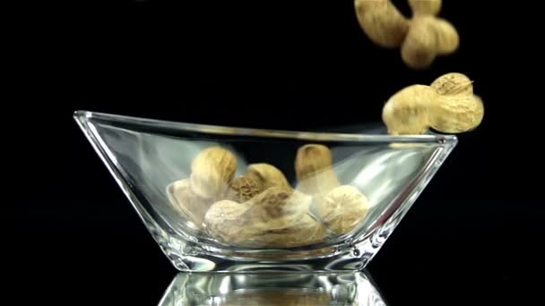 Amendoins estão caindo em vidro no fundo preto em câmera lenta — Vídeo de Stock