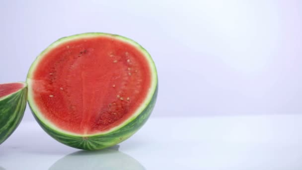 Pan shot of two parts of watermelon white background — Stock Video