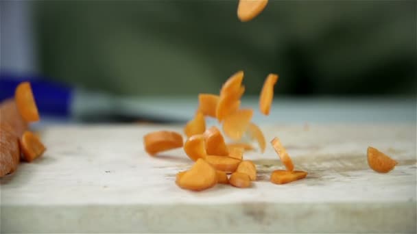 Ahşap bir masa üzerine dilimlenmiş havuç düşen parçaları — Stok video