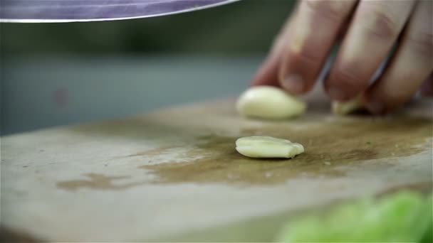 Cortando alho com faca na mesa da cozinha — Vídeo de Stock