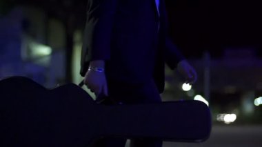 Karanlık gecenin ağır çekimde bir gitar taşıyan adam