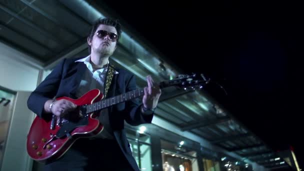 Hombre con gafas de sol tocando la guitarra roja en cámara lenta — Vídeo de stock