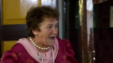 yaşlı bir hizmetçi giyerek bir çay fincan içine çay dökmek çalışıyor