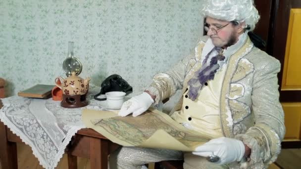 Człowiek w średniowiecznych ubraniach wygląda na starą mapę i kiwa — Wideo stockowe