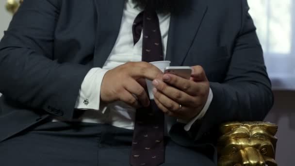 Posh uomo vestito sta digitando nel suo telefono cellulare mentre seduto sulla vecchia sedia — Video Stock