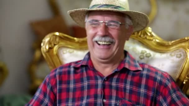 Agricultor sonriendo en una silla dorada — Vídeo de stock