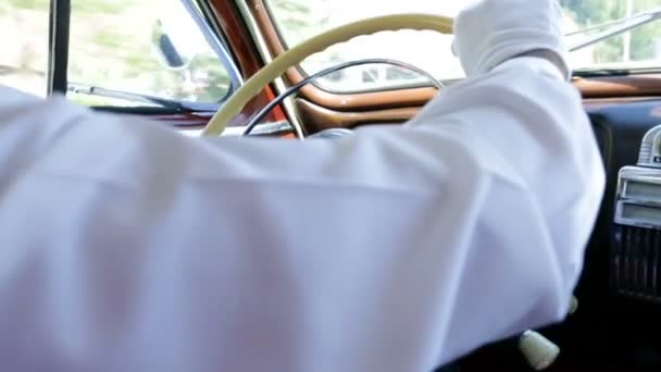 Hombre de camisa blanca volando un volante en coche vintage — Vídeo de stock