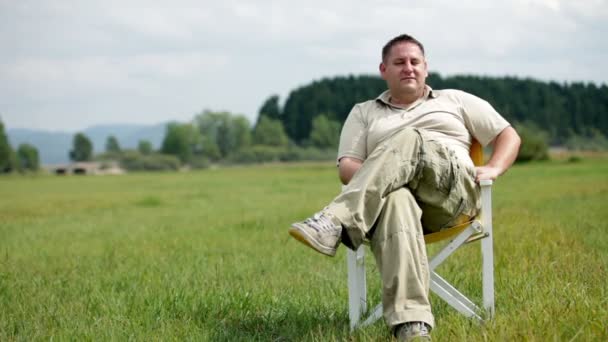 Pan av manliga i ljusa kläder sitter i picknick stol i naturen — Stockvideo