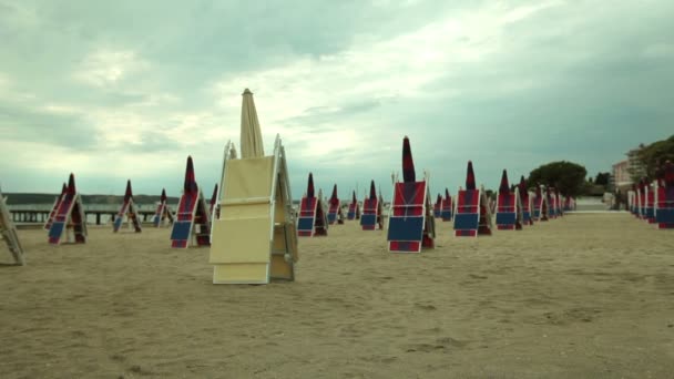 Deckchair e guarda-sóis dispostos na praia arenosa — Vídeo de Stock
