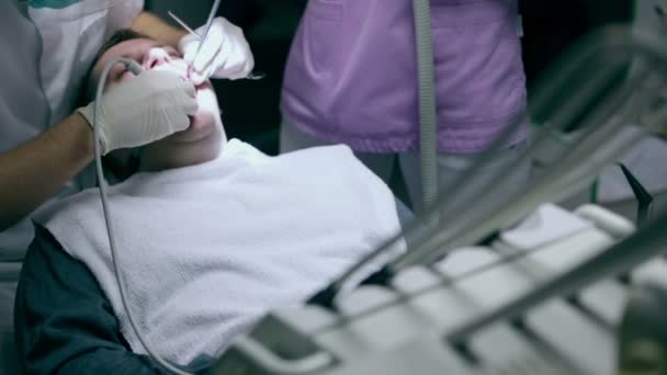 Dentist during his work with the assistant and the client — Stock Video