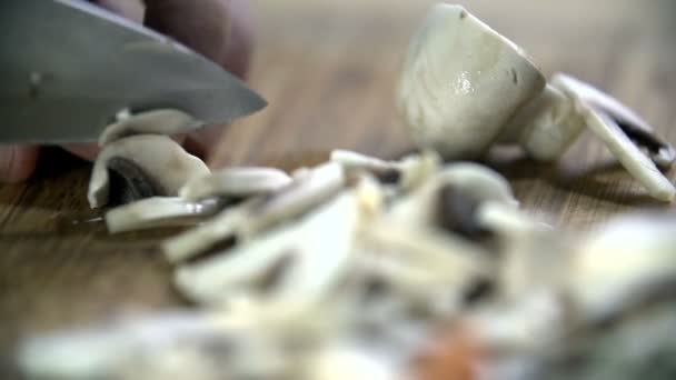Большой кухонный нож, нарезающий маленький гриб — стоковое видео