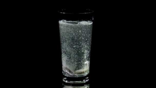 Таблетки растворяются в стакане воды в замедленной съемке — стоковое видео