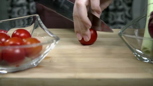 Rebanando tomates pequeños en un escritorio de cocina de madera — Vídeo de stock