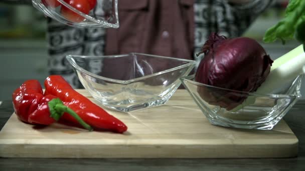 Moviendo tomates pequeños en un plato de vidrio junto al pimiento y una cebolla — Vídeo de stock