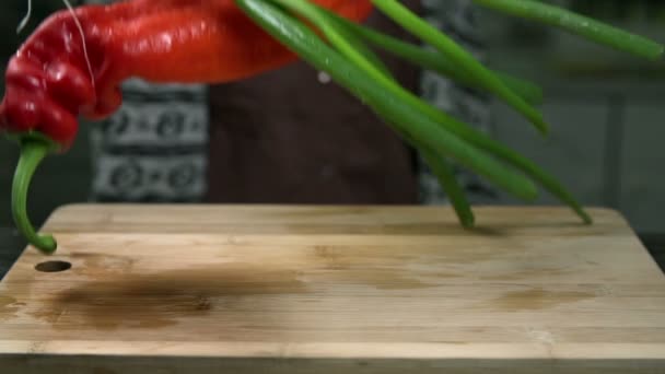 Velké pálivé papriky a cibule klesnout na dřevěný stůl — Stock video