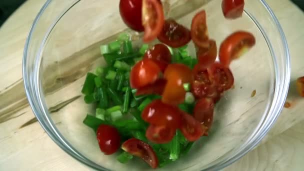 Geschnittene Tomaten fallen in Porree im Glasbecher — Stockvideo