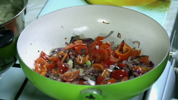 Lanzar pequeños tomates en rodajas en la sartén con cebollas y pimientos — Vídeo de stock