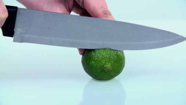 Schneiden einer Limette mit einem Küchenmesser auf weißem Hintergrund in Zeitlupe — Stockvideo