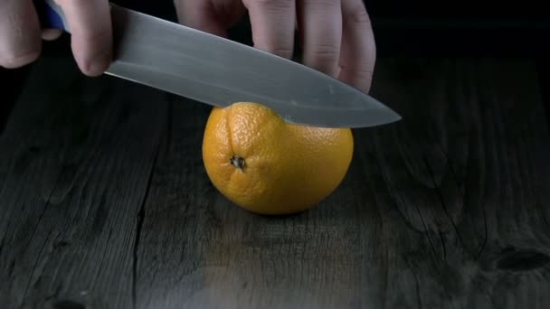 Schneiden einer Orange auf einer Holzoberfläche in Zeitlupe — Stockvideo