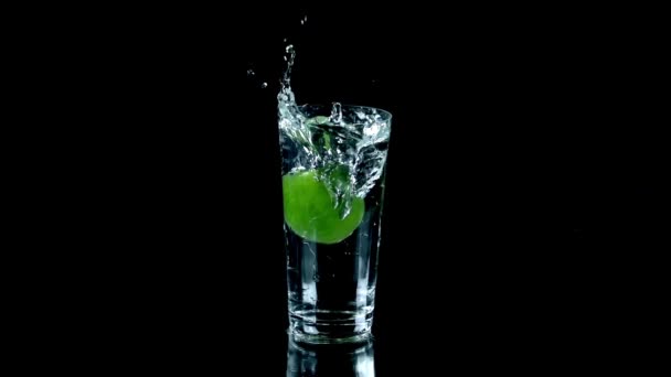 Whole lime falls into glass of water and spurts water around the table — Stock Video