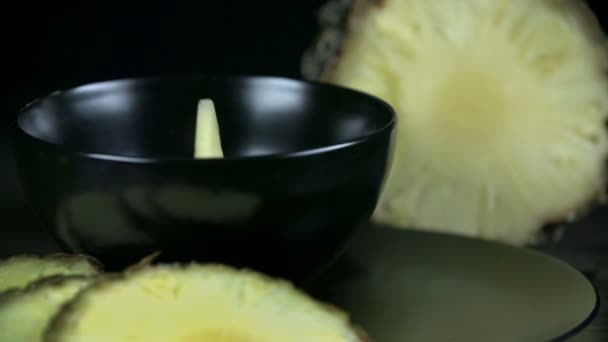 kousky ananasu pádu do černé cup v pomalém pohybu