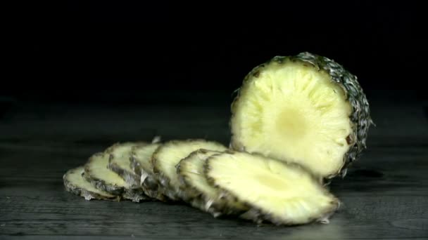 Ananas segmenten vallen op zwarte tabel in slow motion — Stockvideo