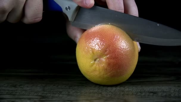 Разрезая грейпфрут пополам на черной поверхности — стоковое видео