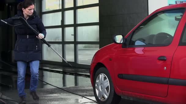 Vrouwelijke schoonmaken van haar auto met druk van het water in slow motion — Stockvideo