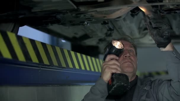 Mekaniker kontrollerar botten av bilen — Stockvideo