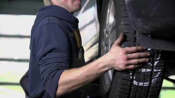 Jovem vulcanizador leva o pneu do carro em slo-mo — Vídeo de Stock