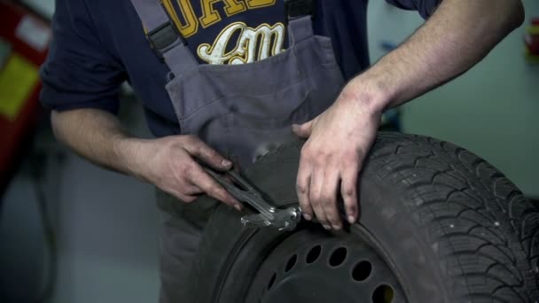 Вулканизатор вбивает металлический кусок в колесо — стоковое видео