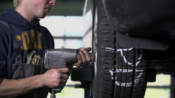 Mecánico aflojando el neumático del coche — Vídeo de stock