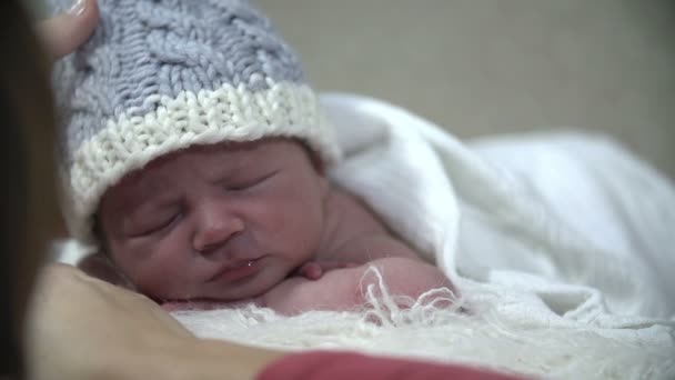 Baby with blue cap rests while being covered with white blanket — Stock Video