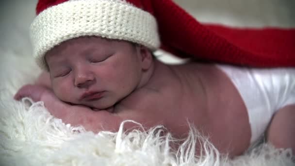 Baby in witte luiers met een lange rode kerstmuts op het hoofd — Stockvideo