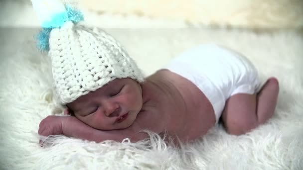 Little baby laying on salty blanket with a white cap — Stock Video