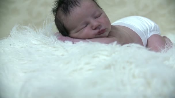 Niño acostado sobre una manta peluda blanca — Vídeo de stock