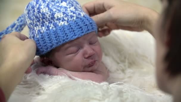 Att sätta en blåaktig mössa till babyns huvud — Stockvideo