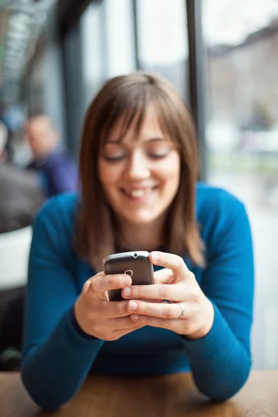 Menina bonita usando telefone inteligente em um café — Fotografia de Stock