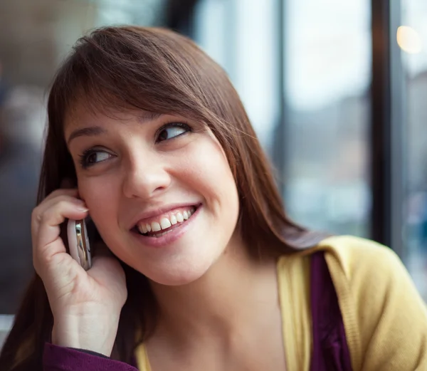 Beautiful young girl on the phone in a cafe — Stock Photo, Image