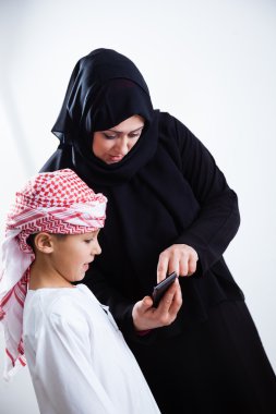 Arabic woman and son using smartphone clipart
