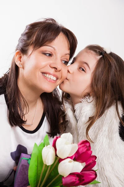 Girl kissing and giving mother flowers — Stock Photo, Image