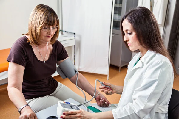 Medico controllando la pressione sanguigna alla donna — Foto Stock