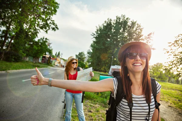 Toeristische meisjes liften op weg — Stockfoto