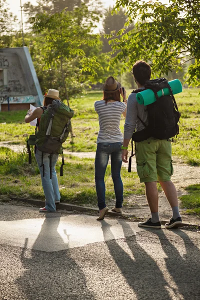 Turistas con mochilas caminando por la carretera — Foto de Stock