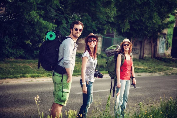 Turistas con mochilas caminando por la carretera — Foto de Stock